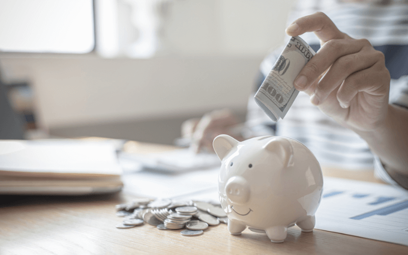 Image of a hand putting money in piggymoney bank