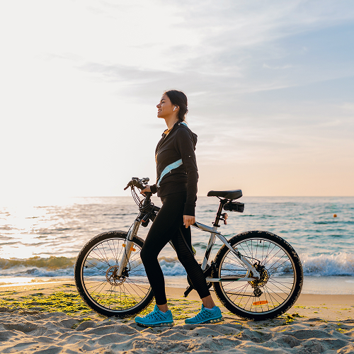 Small image of a person riding a bike along a coast
